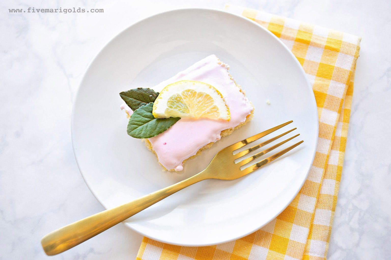 Sheet Cake with pink frosting and lemon slices on a white plate