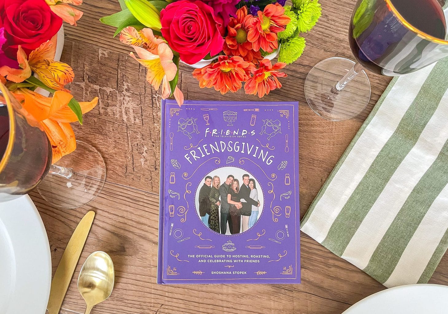 Purple Friendsgiving book on a table next to a colorful flower centerpiece.